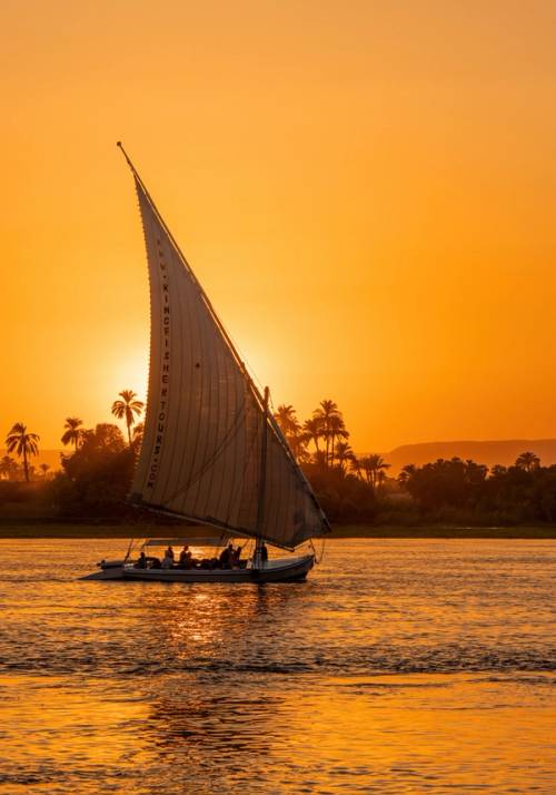 sailing boat on the Nile river with red sun behind