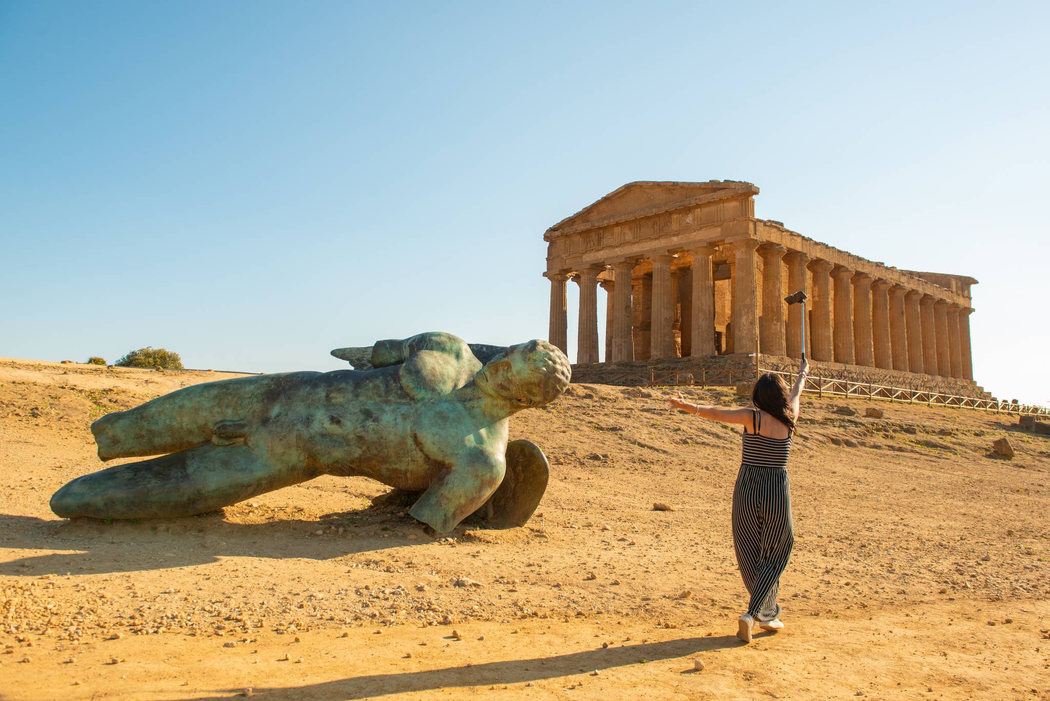 donna nella valle dei templi davanti alla statua di icaro caduto