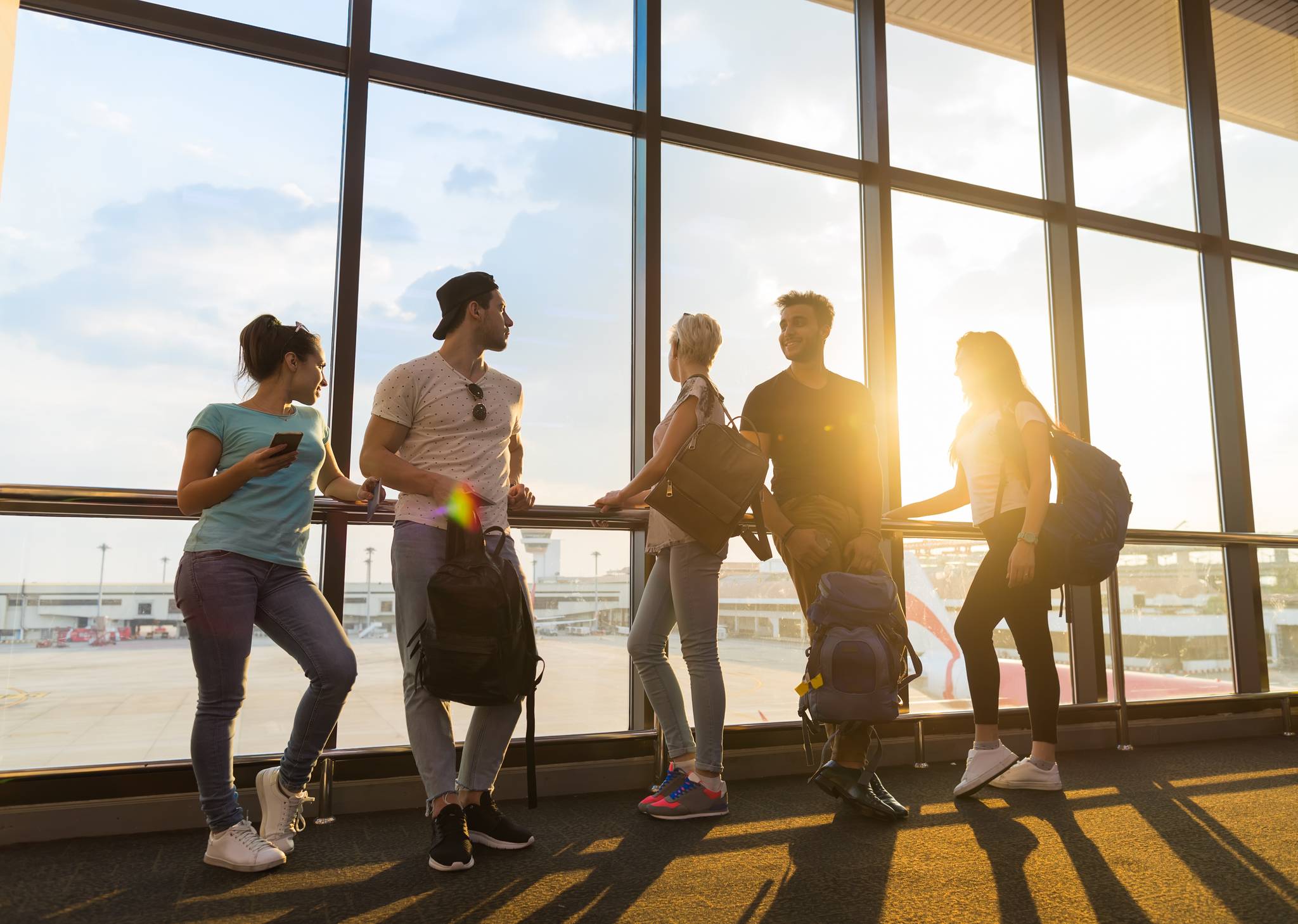 gruppo di ragazzi e ragazze in aeroporto al tramonto