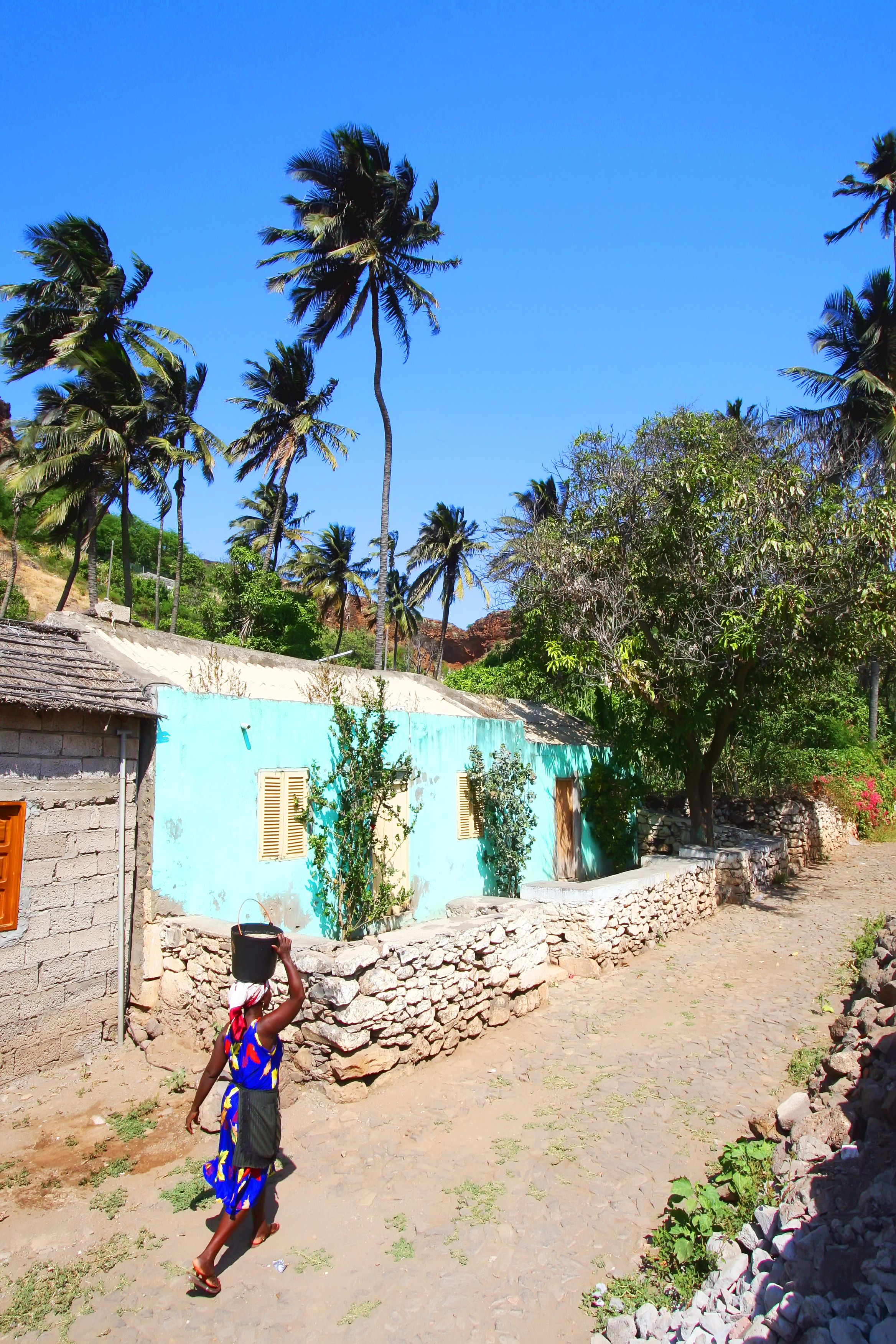 donna trasporta acqua sulla testa in un villaggio colorato