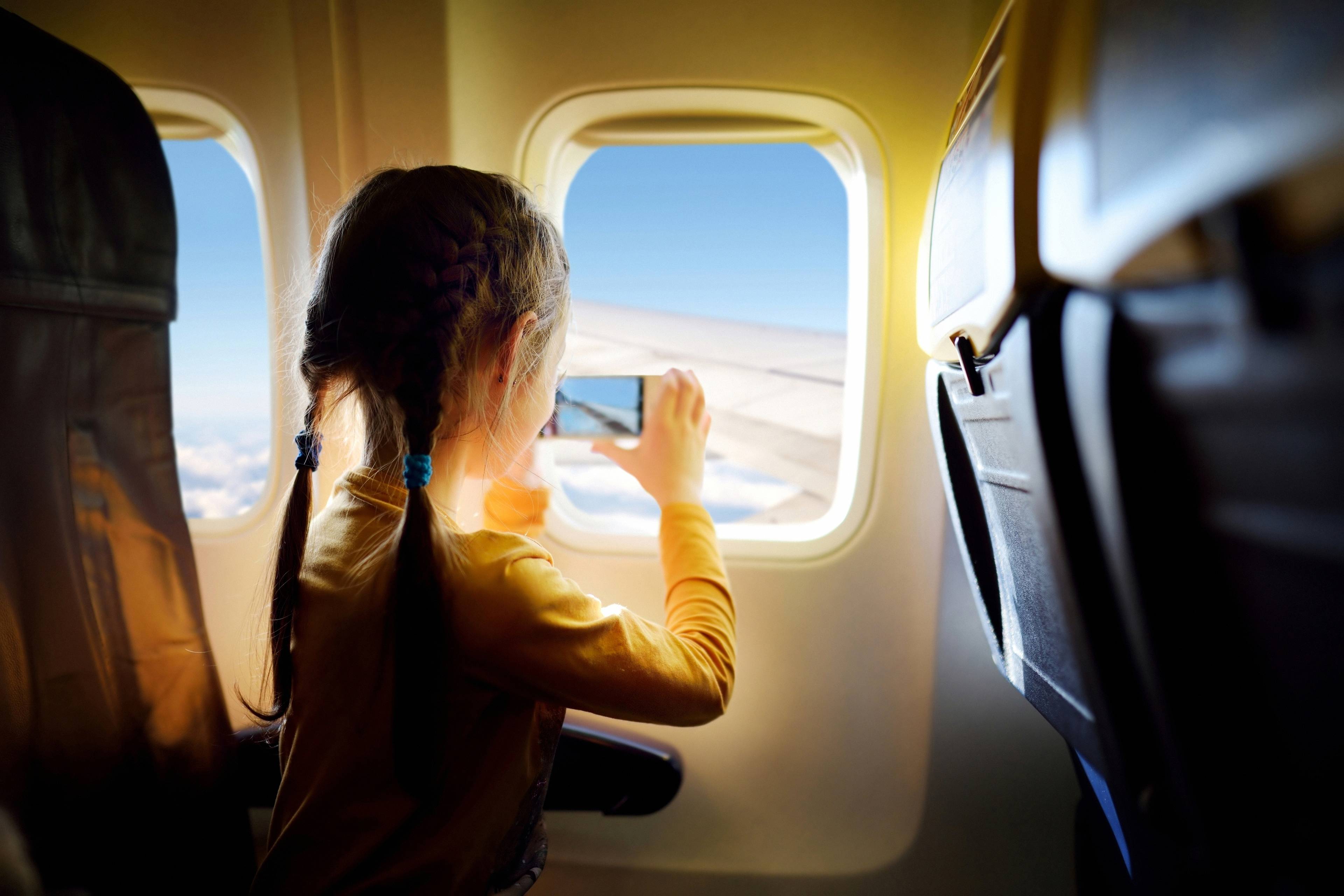 bambina scatta foto con cellulare da finestrino in aereo
