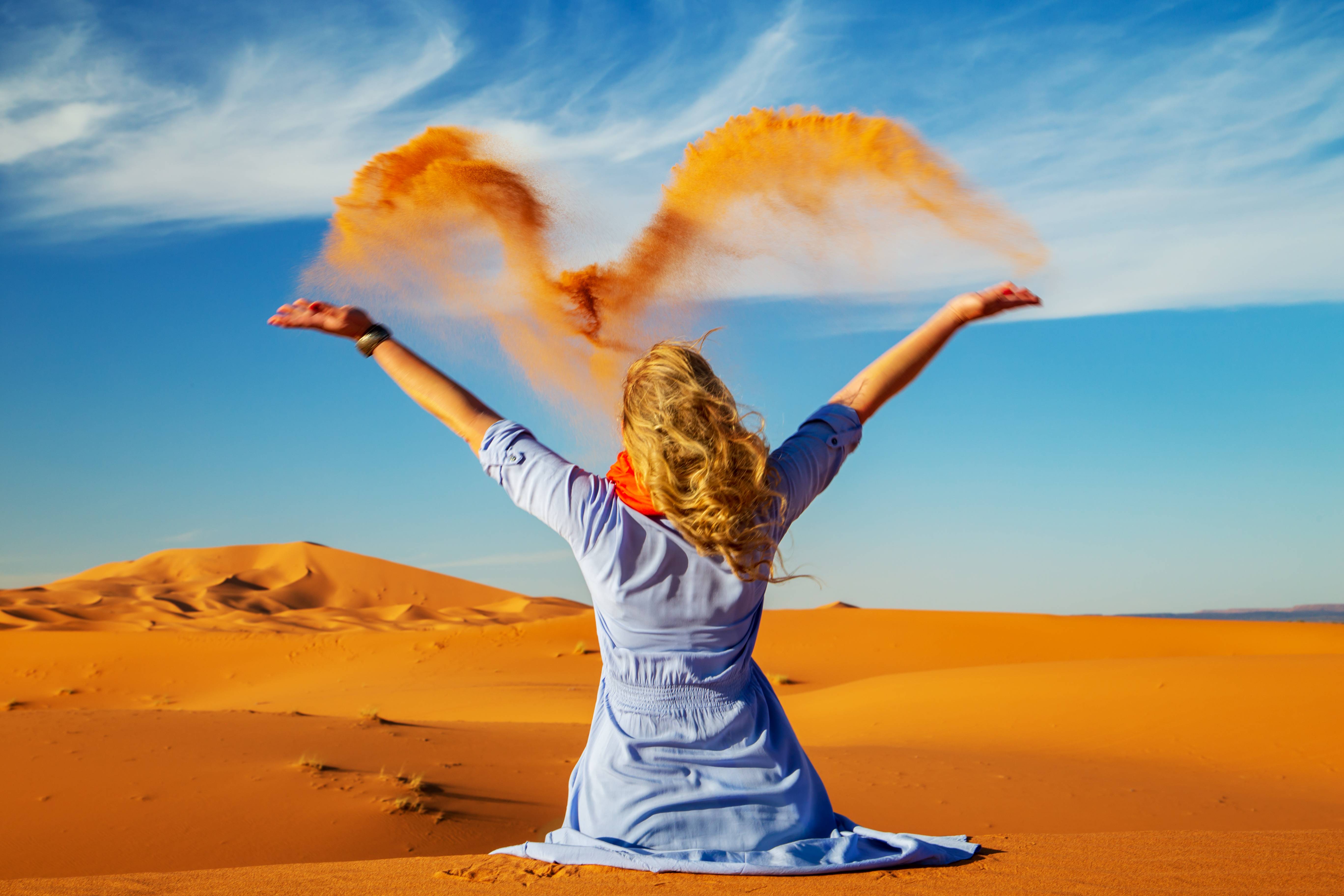 donna lancia sabbia nel deserto di merzouga in marocco