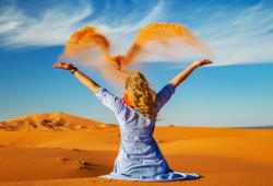 donna lancia sabbia nel deserto di merzouga in marocco