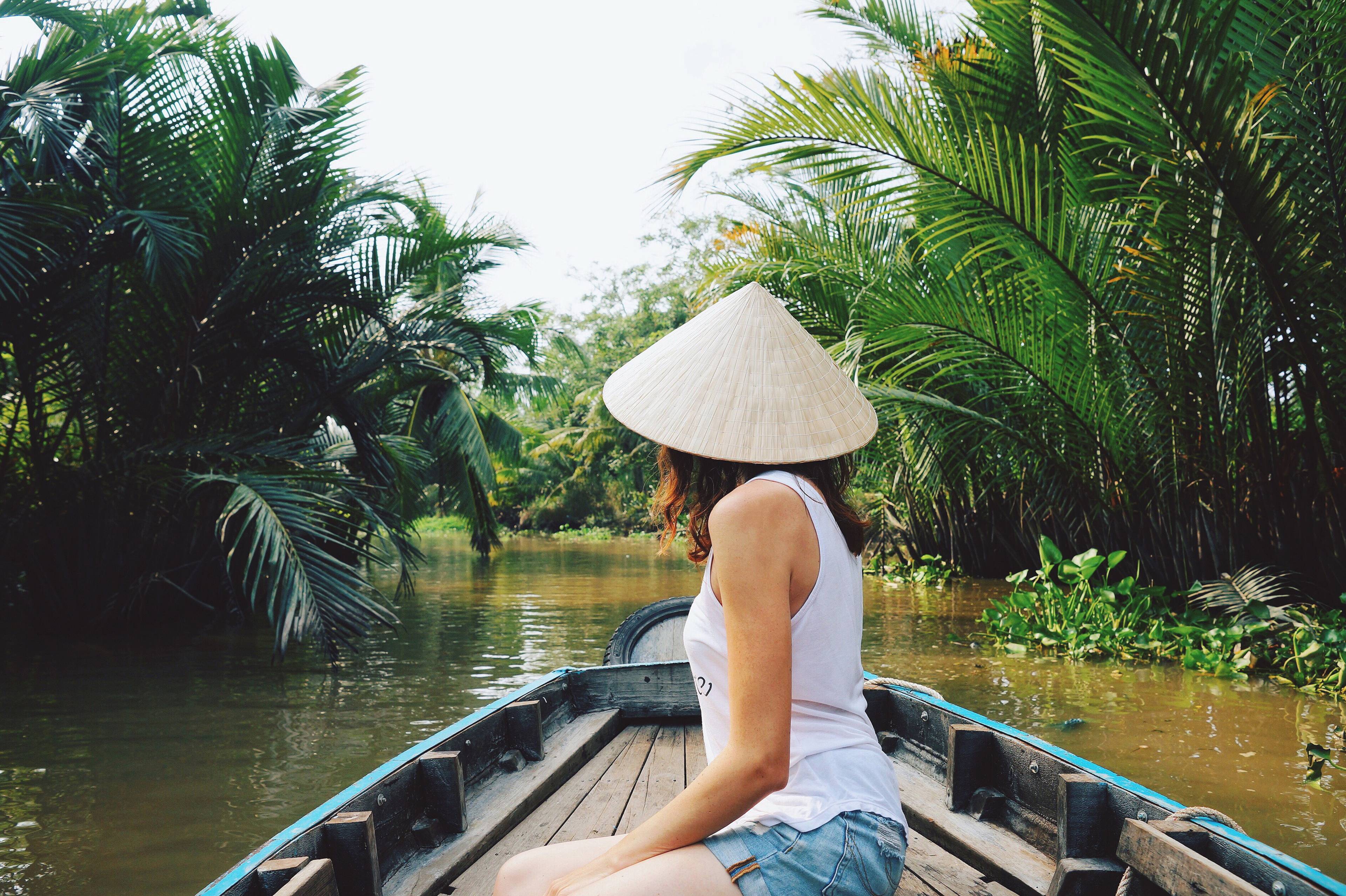 ragazza con cappello tradizionale in barca su fiume in vietnam
