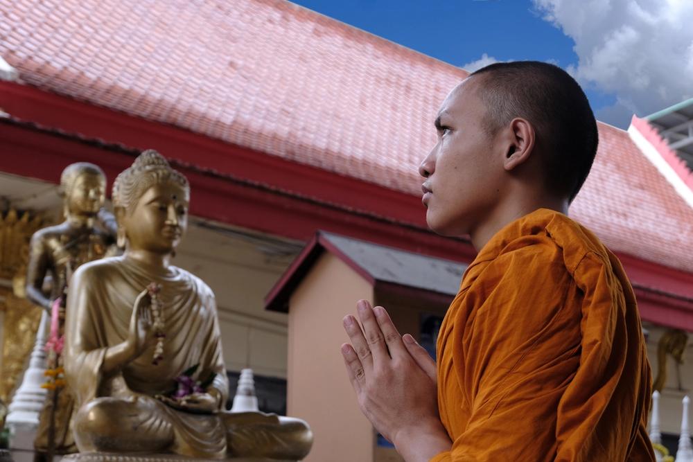monaco tibetano prega statua di buddha