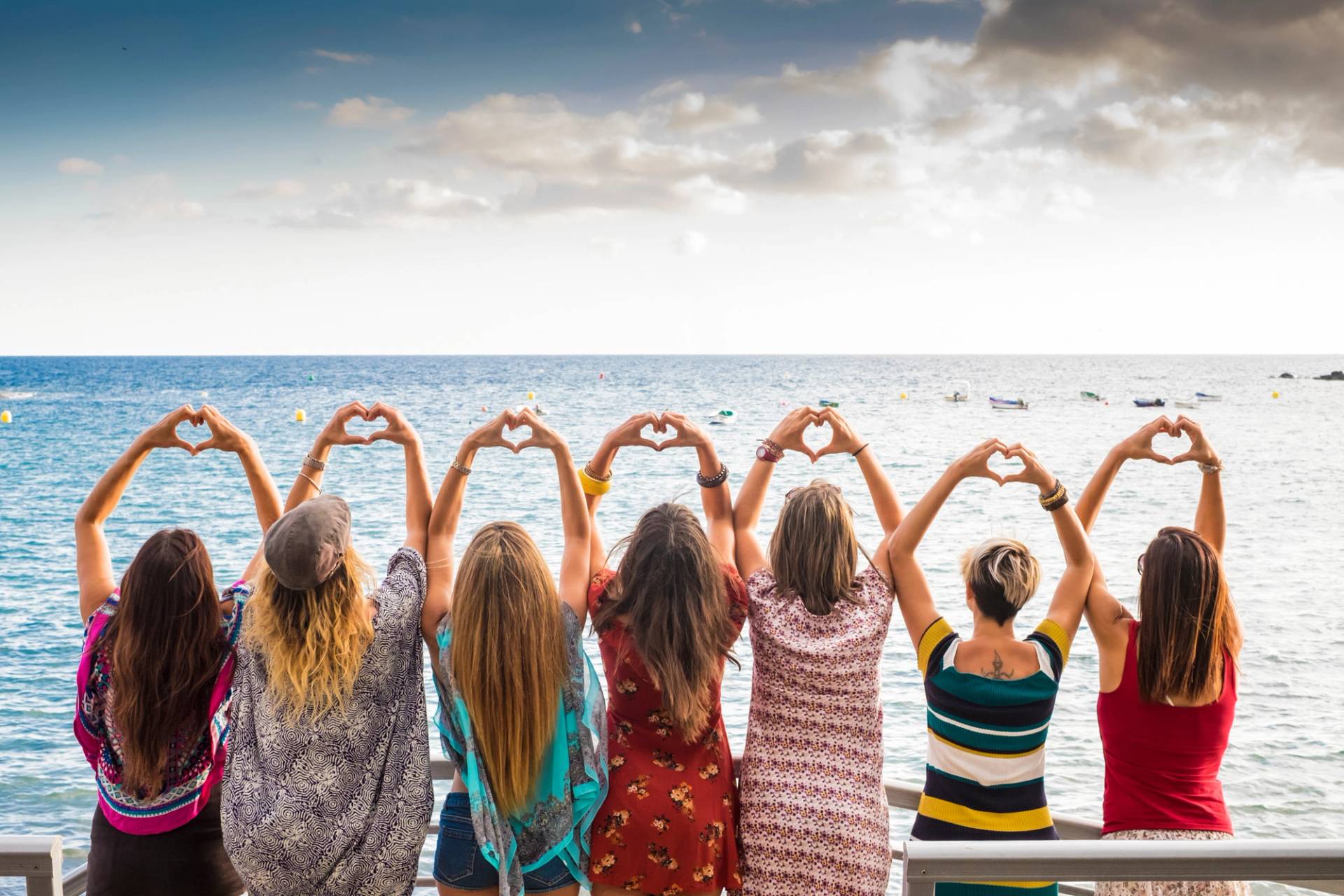 gruppo di done davanti al mare cuore con le mani