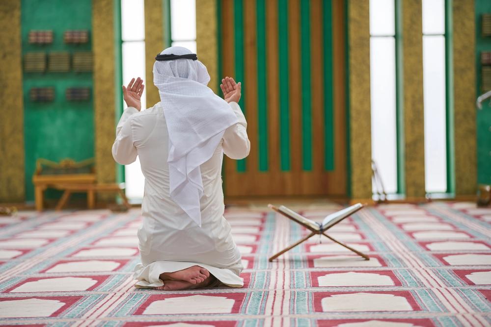 uomo islamico prega in moschea con corano