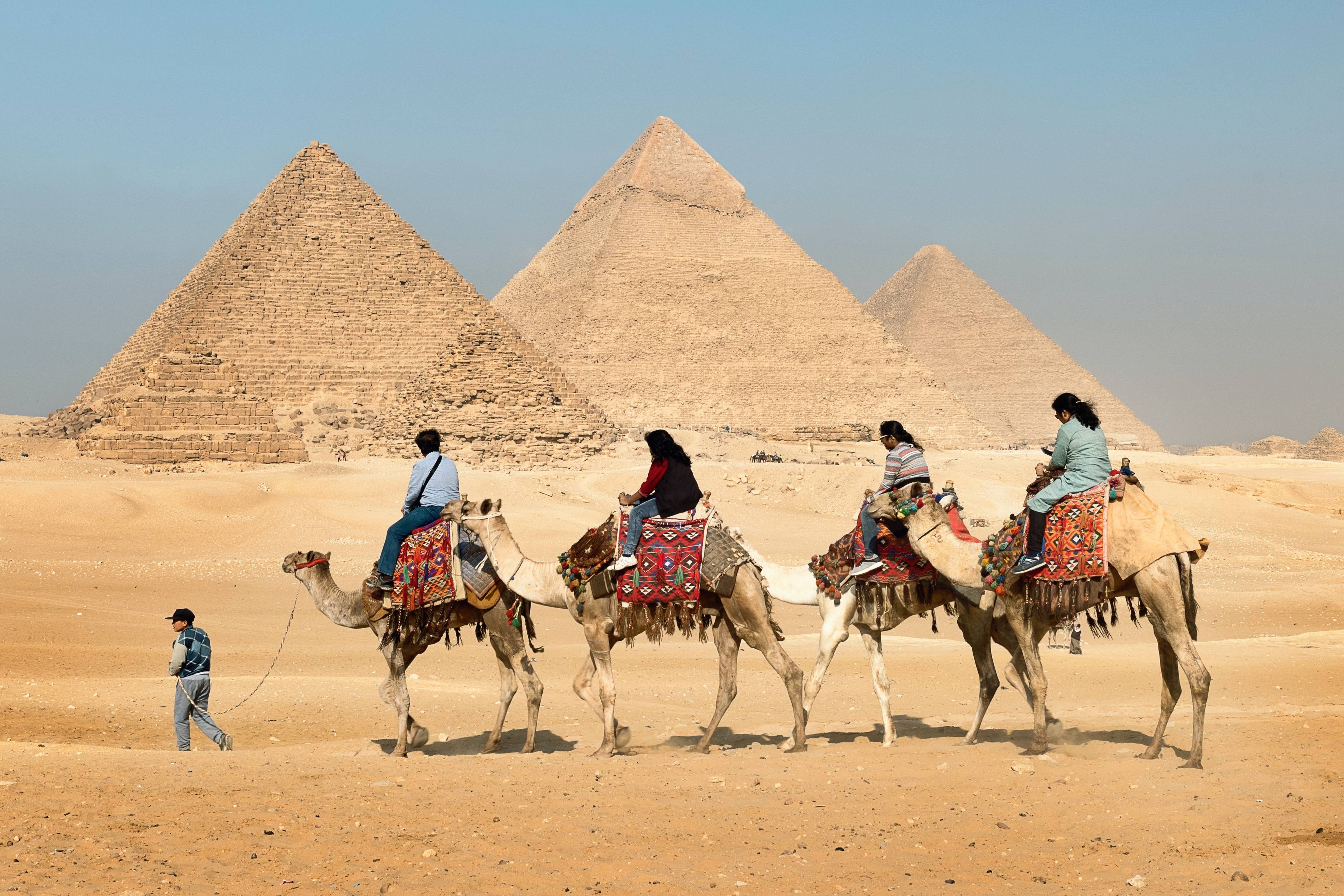 turisti nel deserto a dorso di cammello