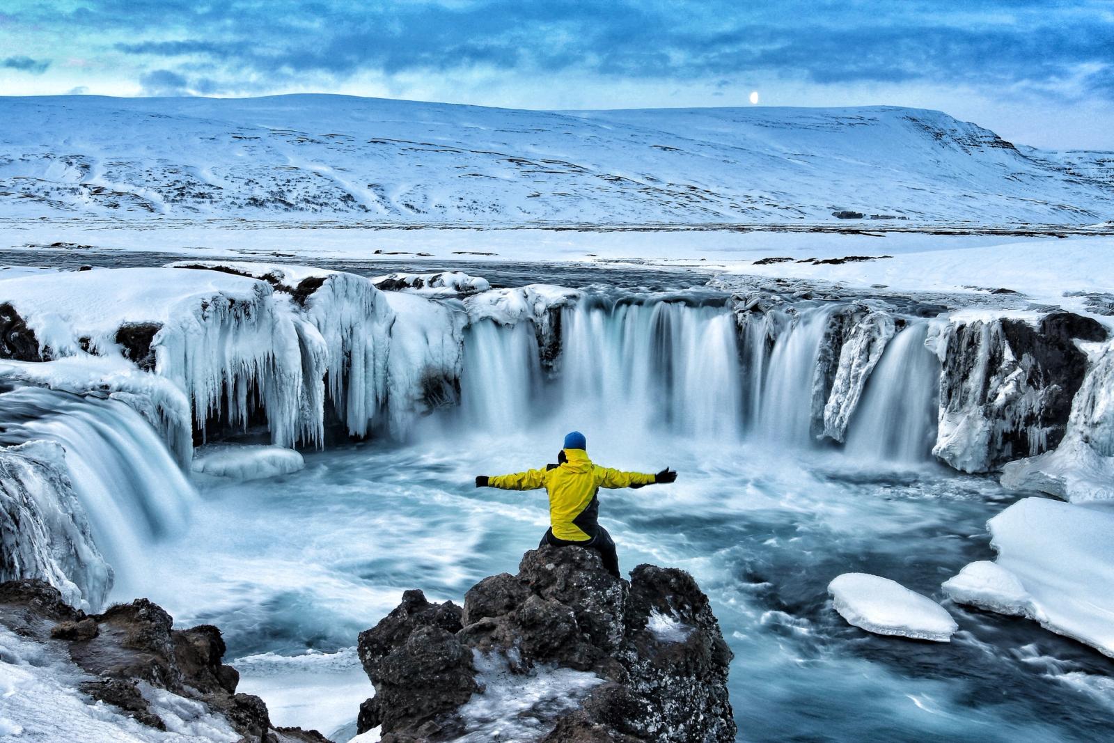 uomo davanti a cascata ghiacciata in islanda