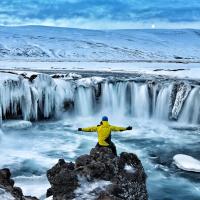 uomo davanti a cascata ghiacciata in islanda