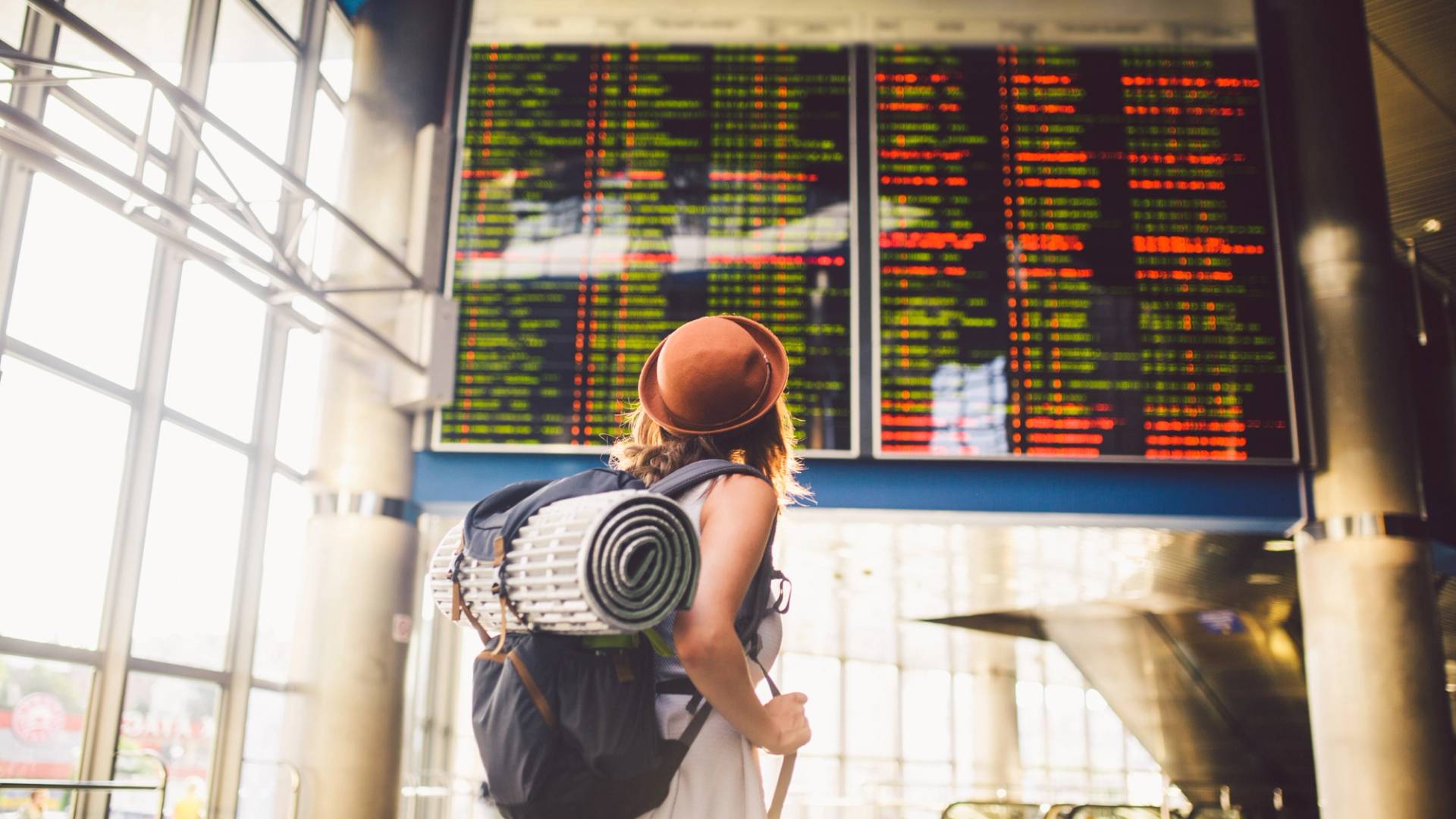 backpacker girl in front of an airport departure board