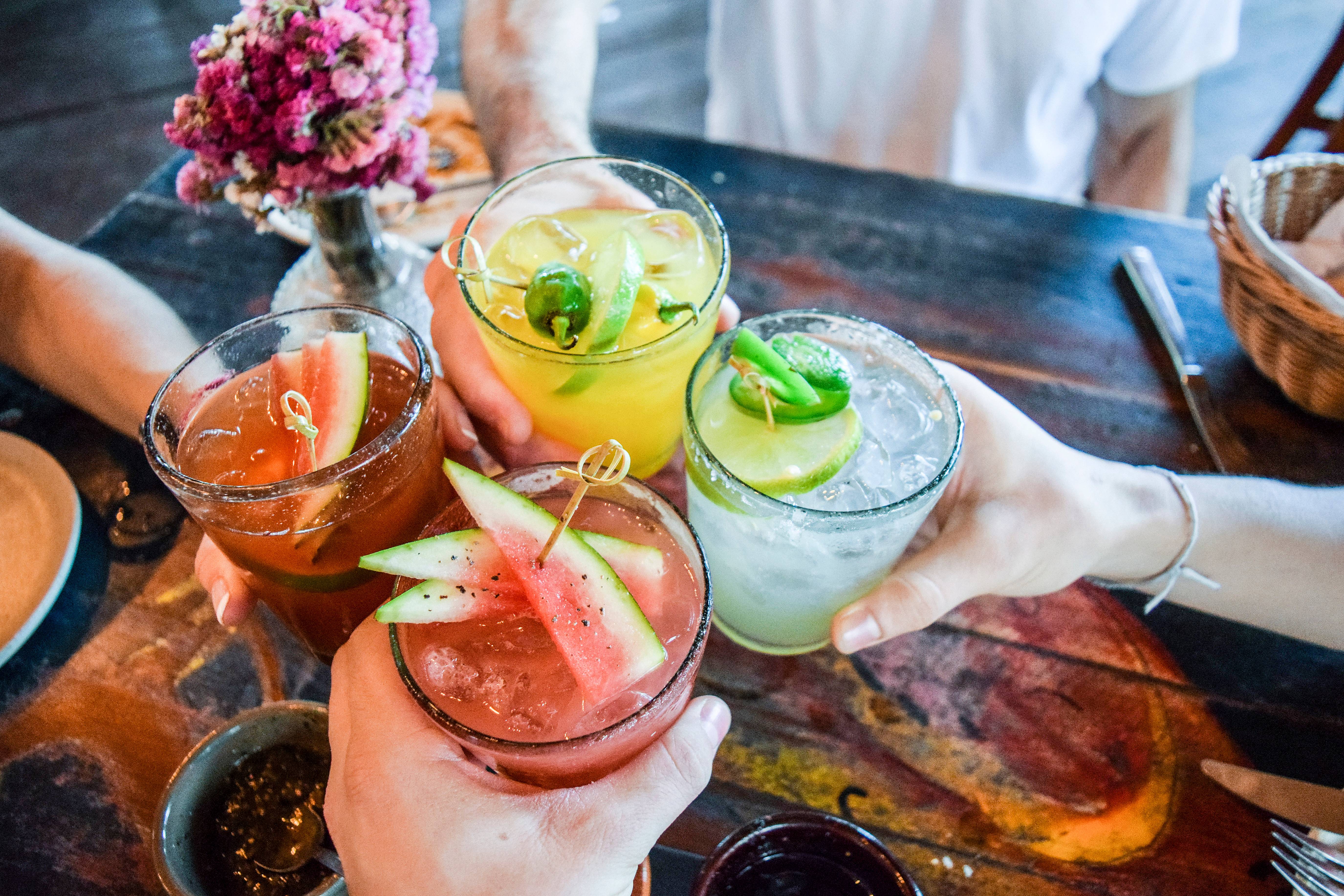 gruppo di persone che brinda con cocktails colorati