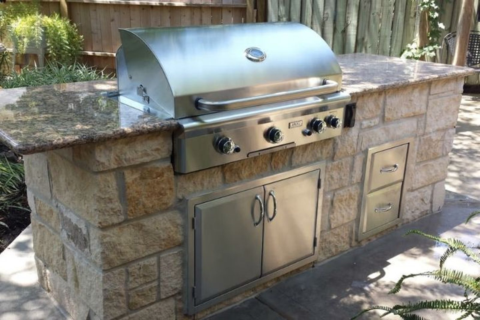Stainless steel built-in grill installed in a stone outdoor kitchen island