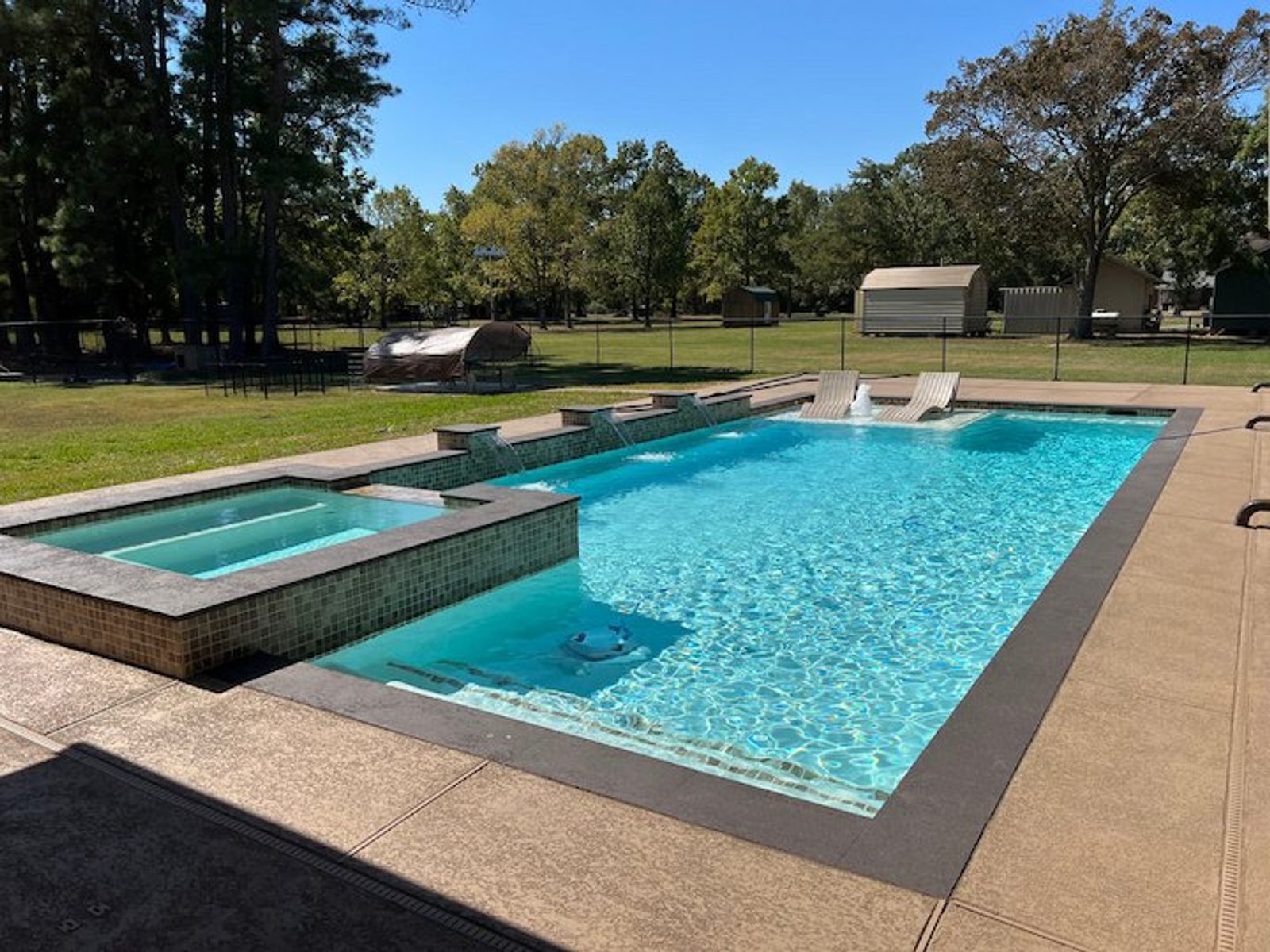 Modern backyard pool featuring a raised spa and shallow ledge loungers