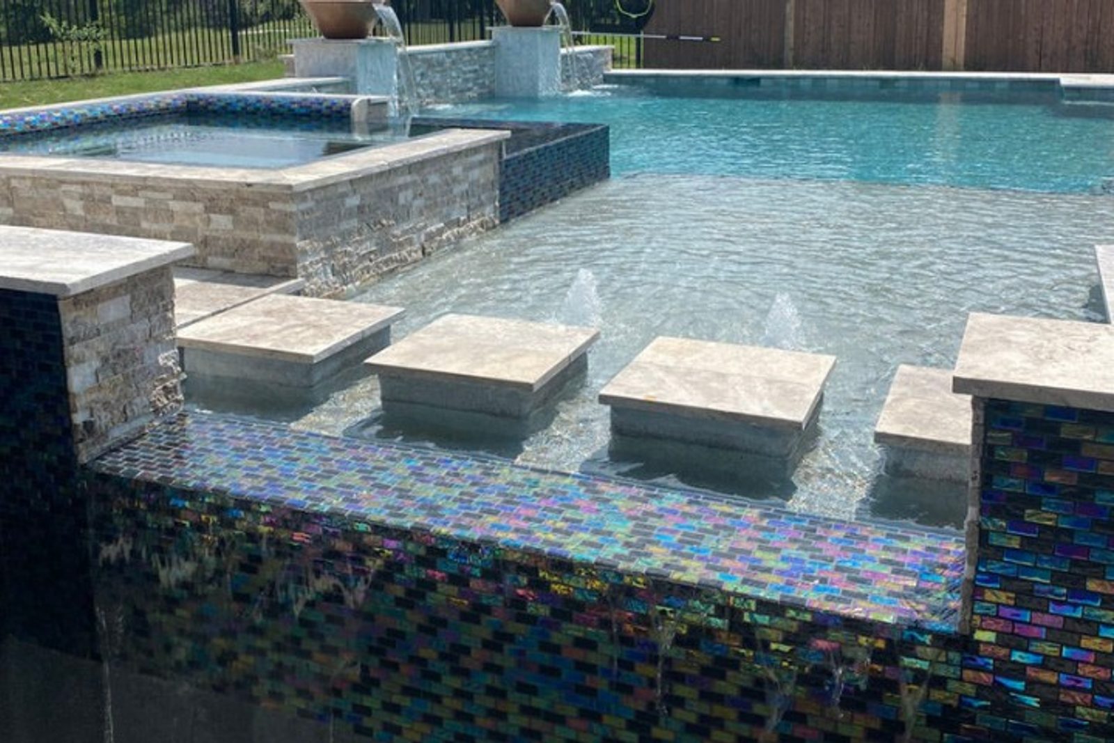Decorative pool tile and spillover water feature in a renovated Houston pool