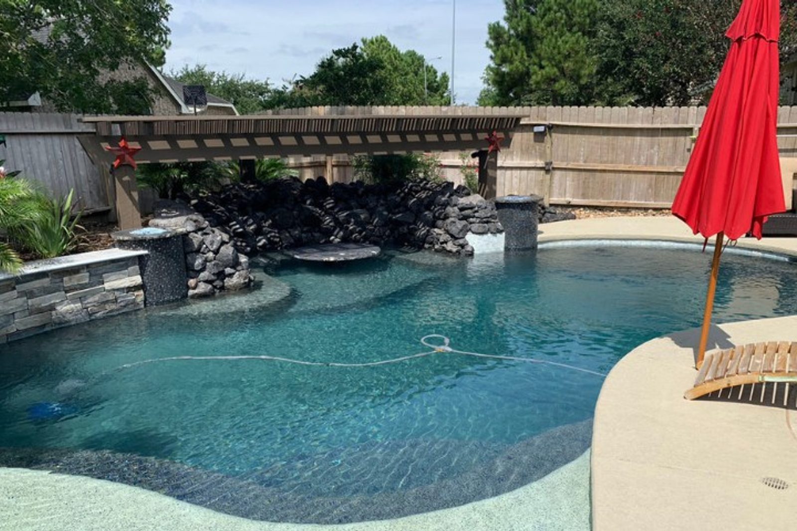 Swim-up seating with natural stone accents and water feature, pool renovation Houston
