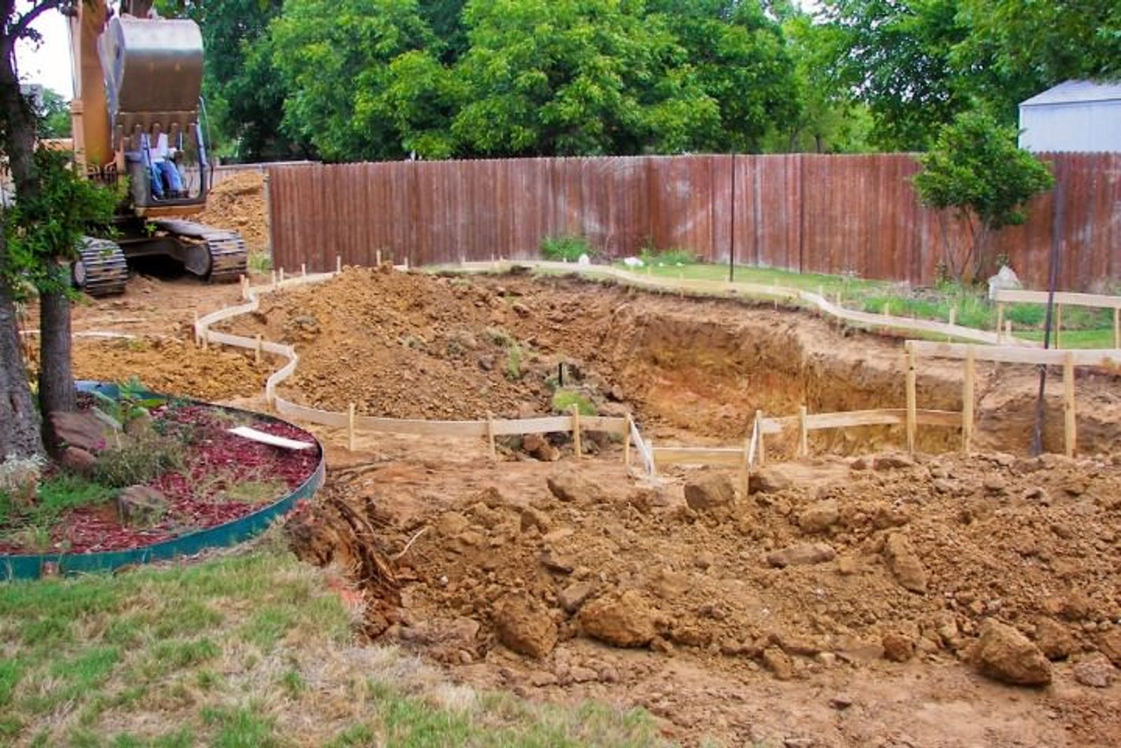 Heavy equipment digging outlined pool area before rebar installation and structural work