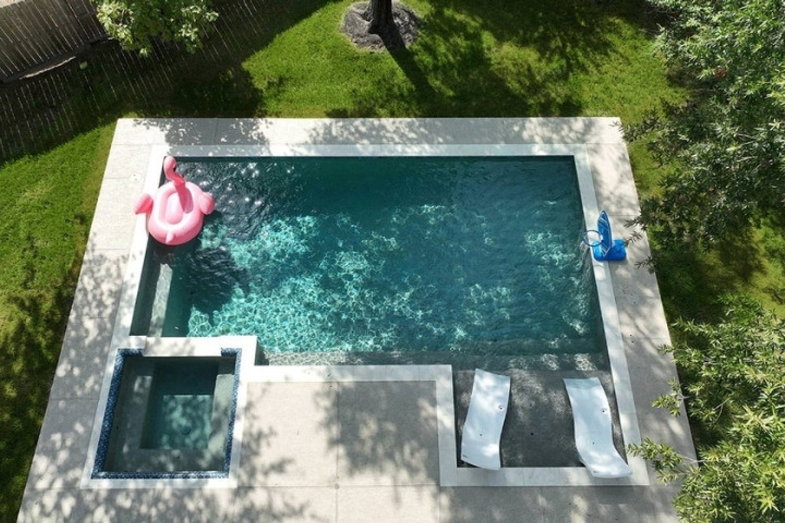 Geometric backyard pool design with attached spa and surrounding patio area in a Texas home