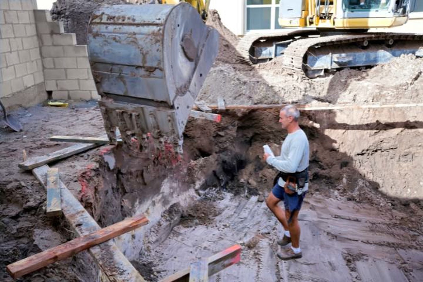Professional pool builder inspecting the construction site for a custom pool and landscaping