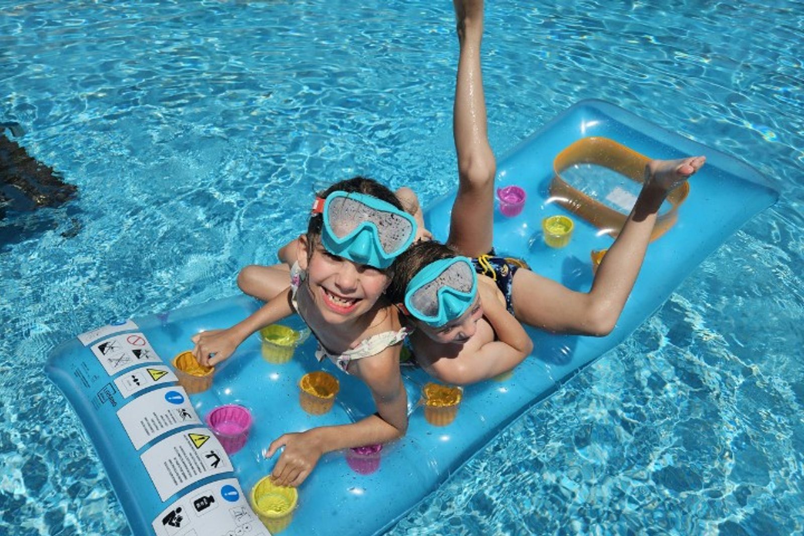 Children wearing goggles on a pool float in a safe swimming pool