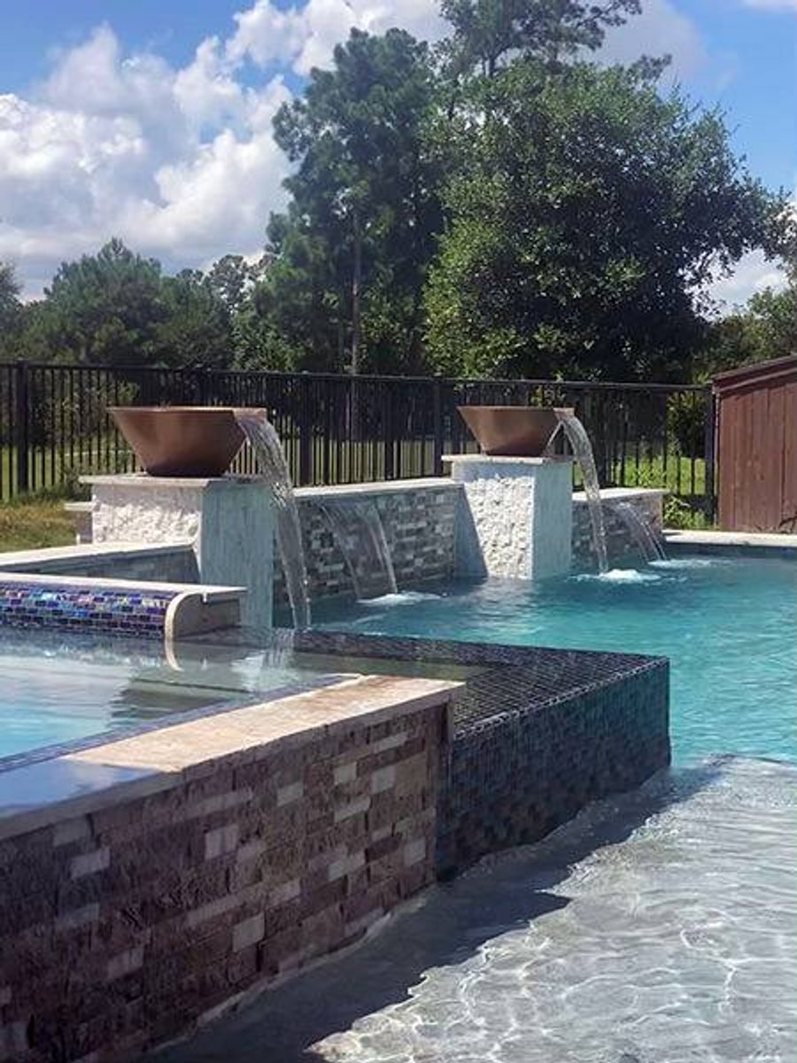 Renovated backyard swimming pool with cascading waterfalls and raised spa in Houston
