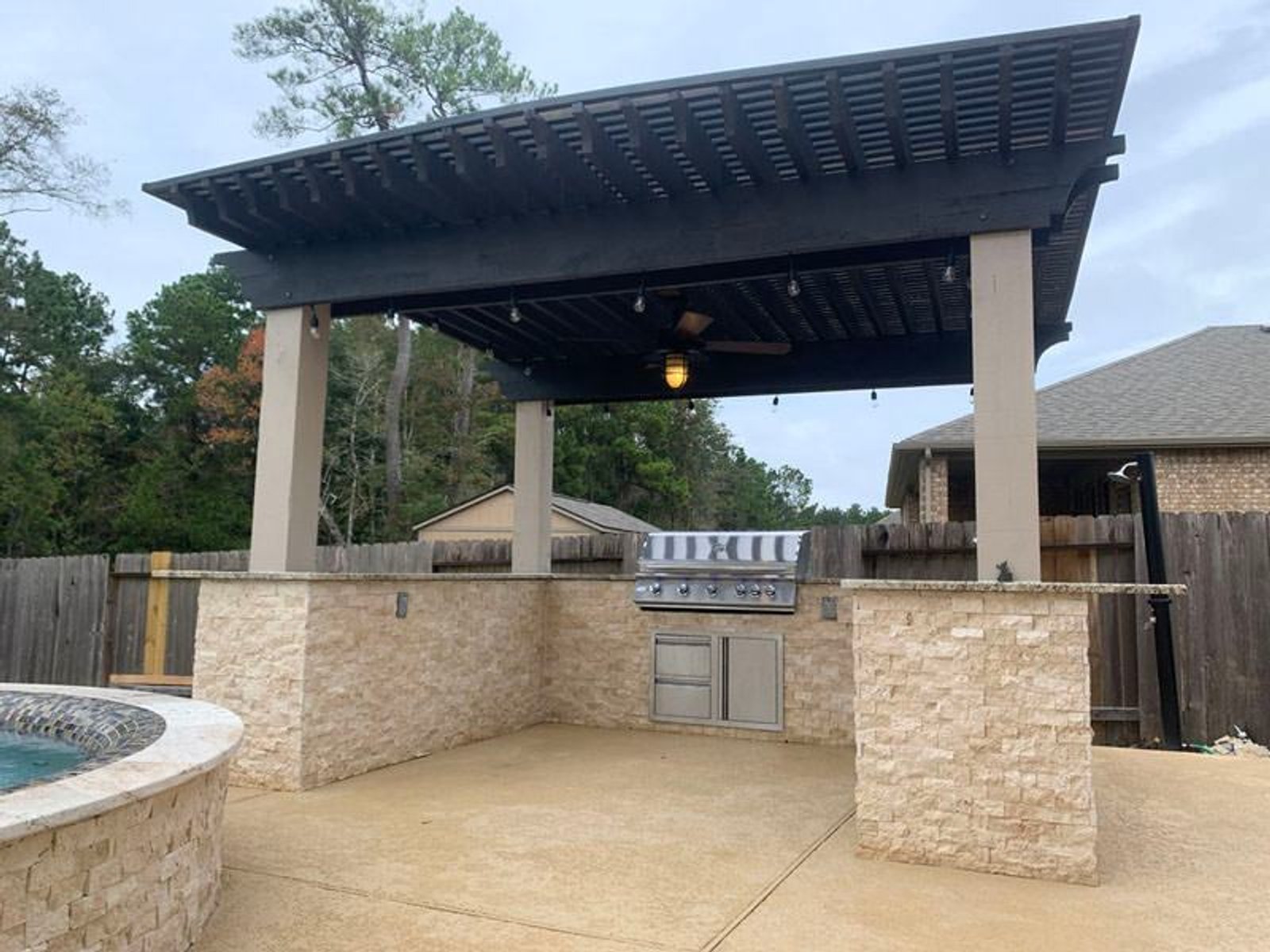 Stylish outdoor kitchen in Houston with pergola roofing and stone countertops