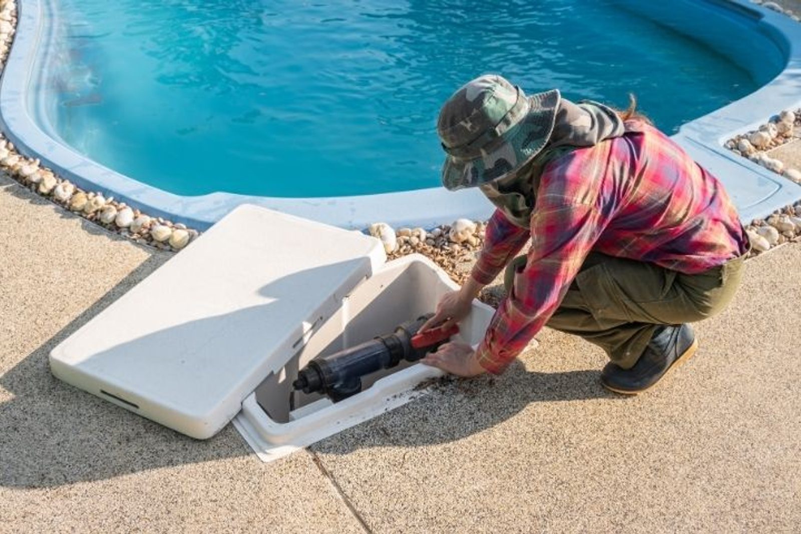 Pool technician inspecting equipment beside a swimming pool after heavy rain in Humble, TX