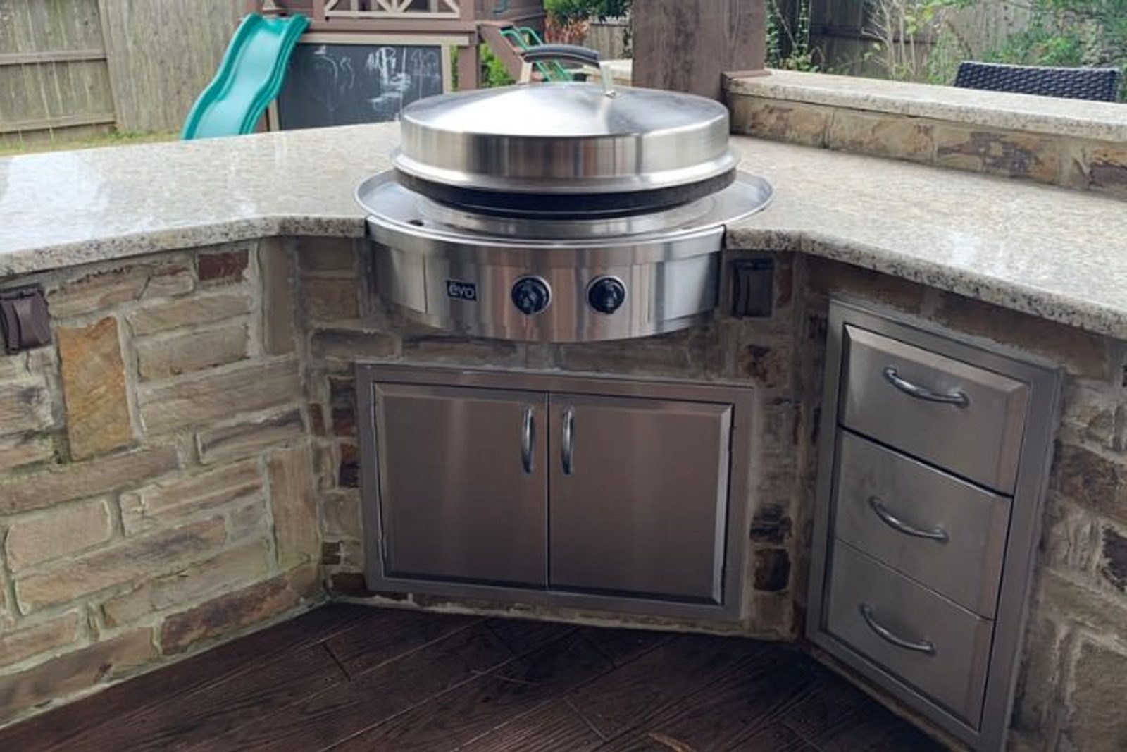 Houston outdoor kitchen with stainless steel cabinet storage, corner cooktop, stone cladding, and granite countertop