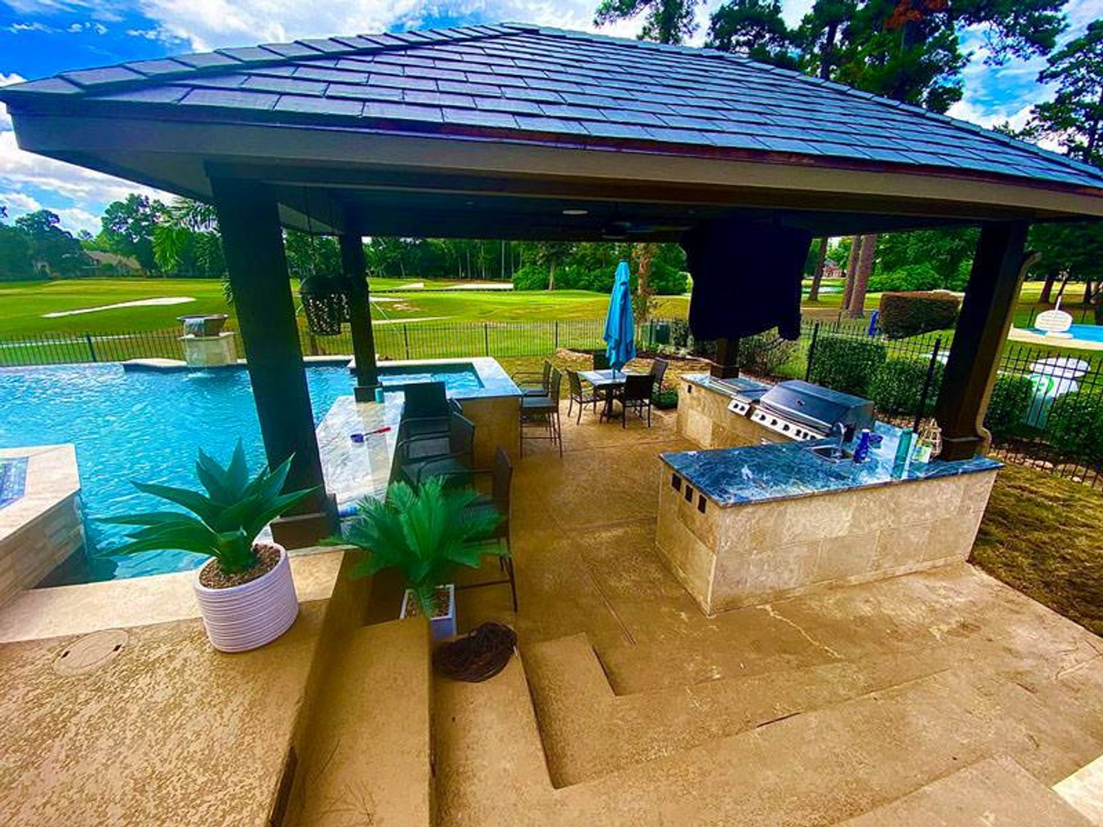 Houston backyard kitchen with shaded patio, stainless steel appliances, and pool view