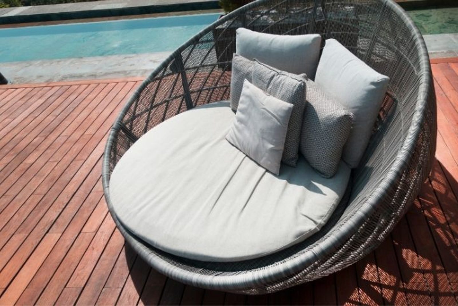 Wicker lounge chair with cushions beside swimming pool