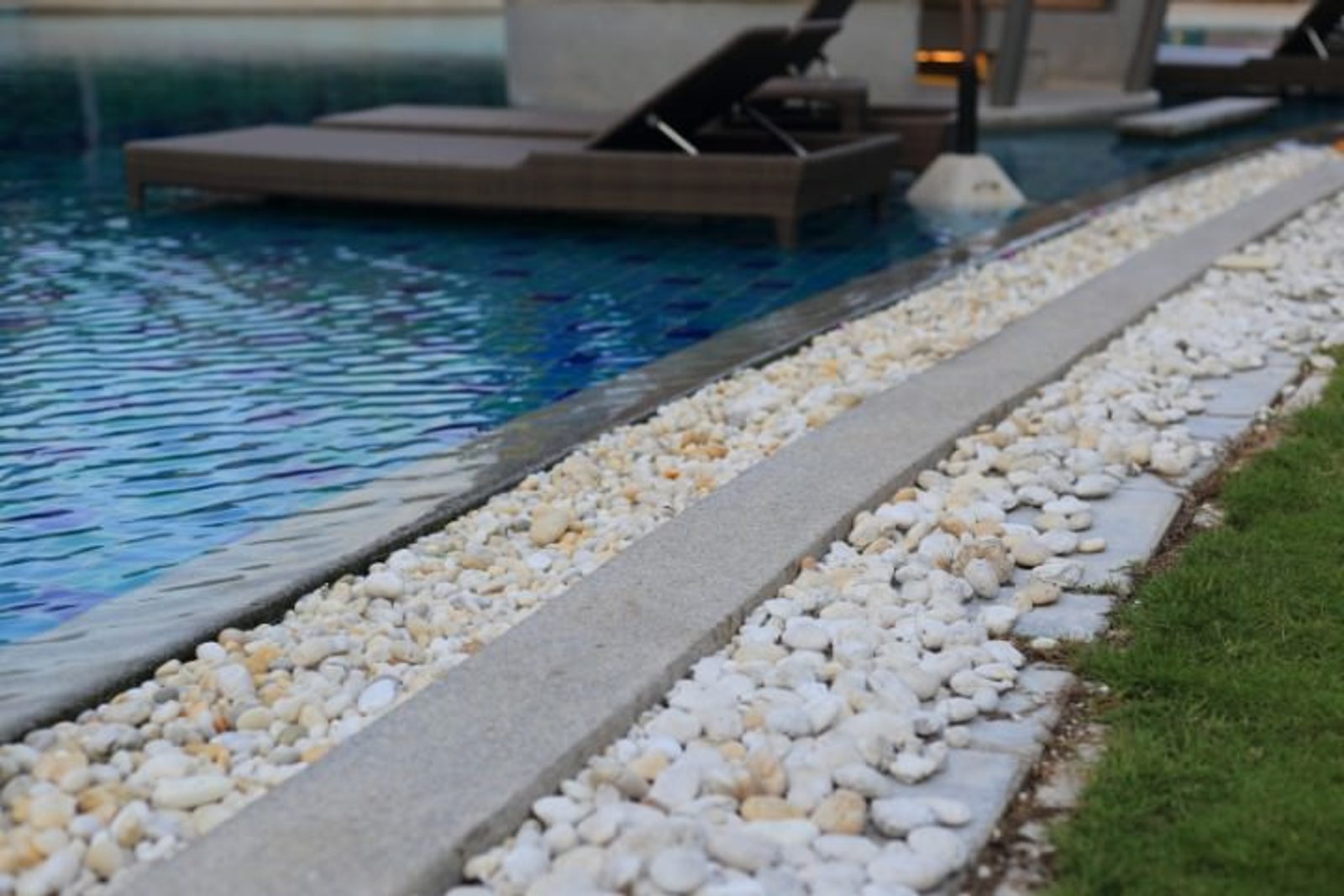 Poolside drainage border with smooth stones for a sustainable pool design