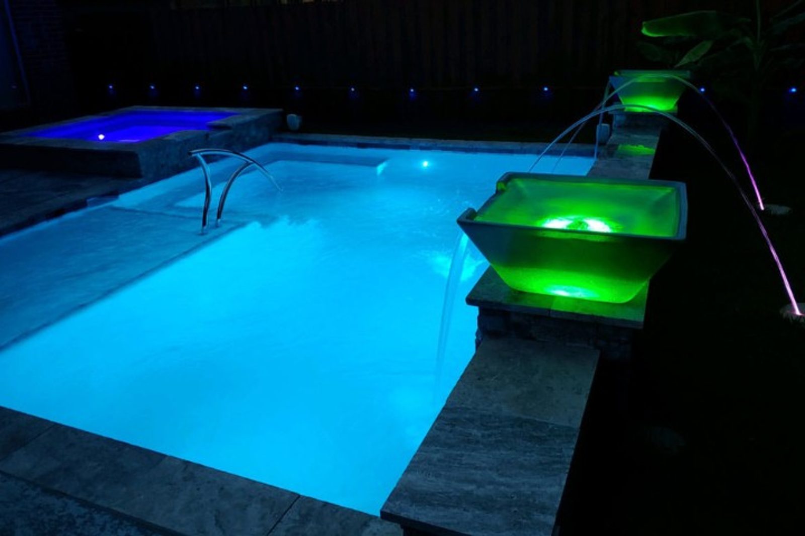 Pool illuminated with modern LED lights and glowing features as part of pool remodel