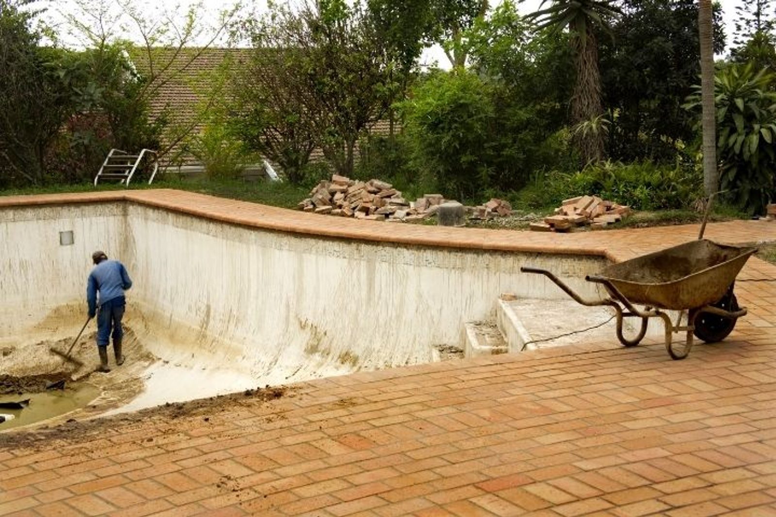 Worker removing worn material from an old pool surface during resurfacing preparation