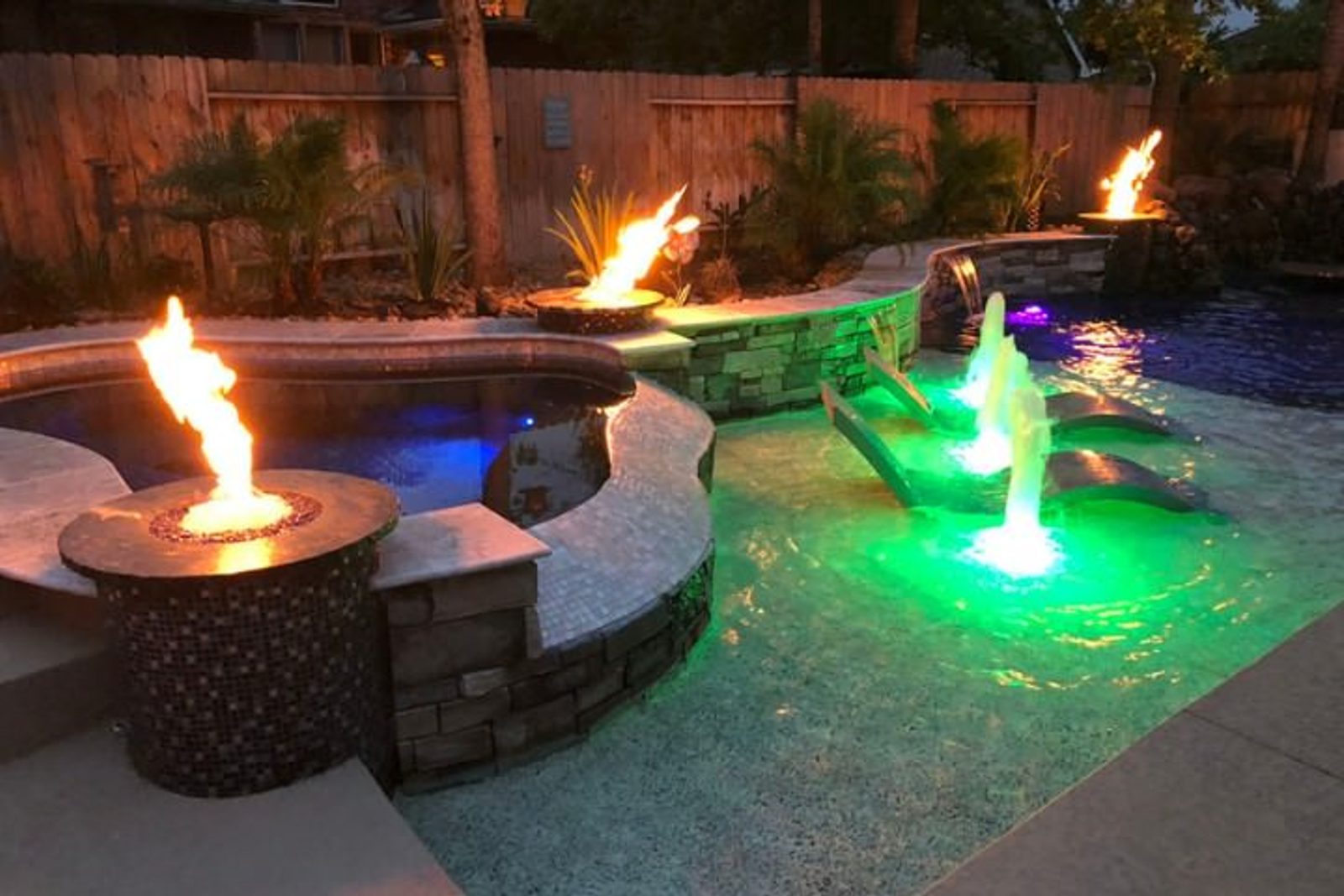Luxury pool with fire and water bowls, creating a dramatic nighttime ambiance and visual contrast