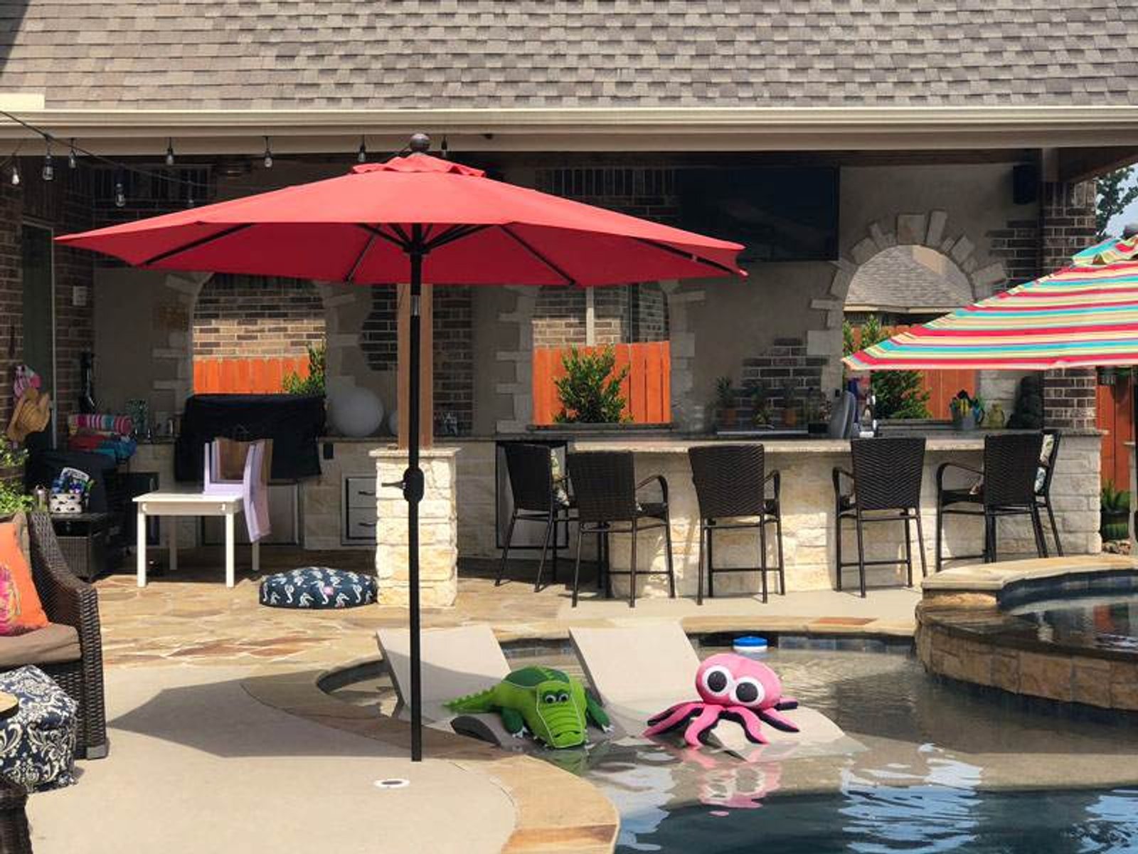 Outdoor living space with a shaded bar and seating area, and colorful next to a swimming pool