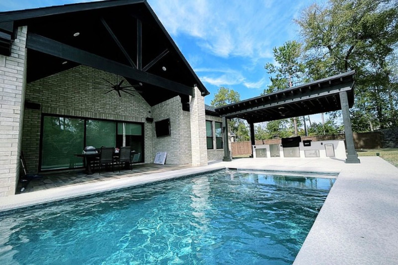 Minimalist Houston pool and patio design featuring classic black structural elements