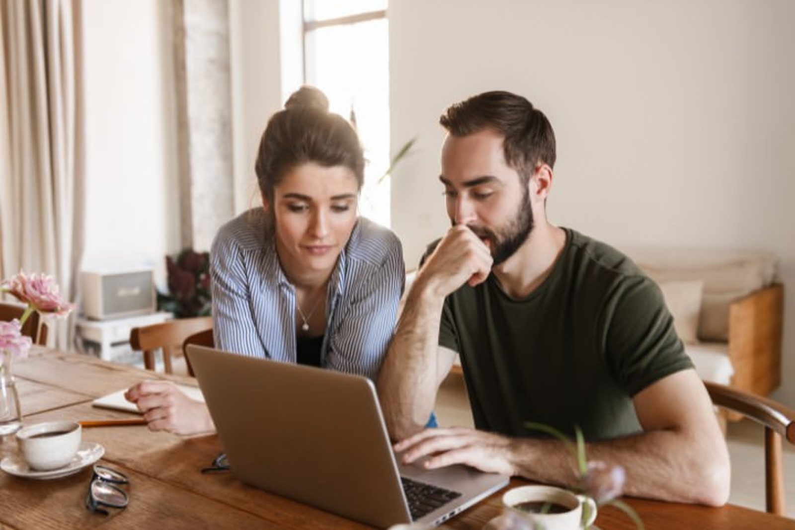 Homeowners comparing pool automation options and installation costs on a laptop