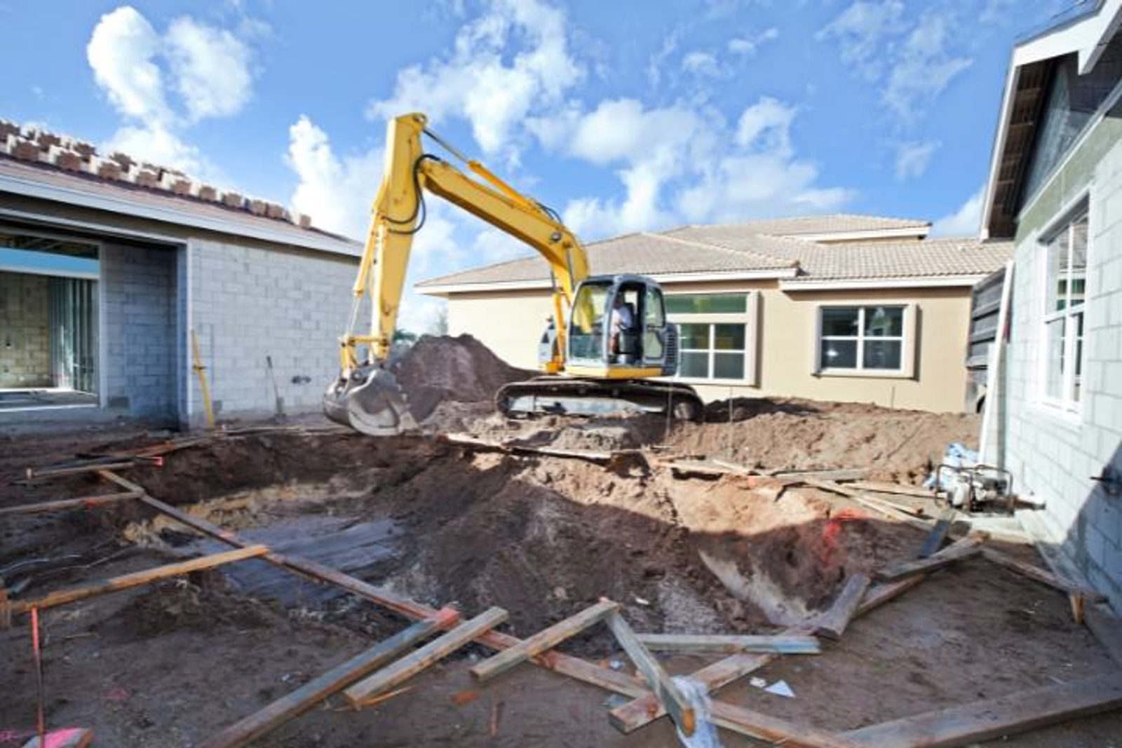Excavator digging inground pool in Houston backyard, contractor with complete permits and licenses