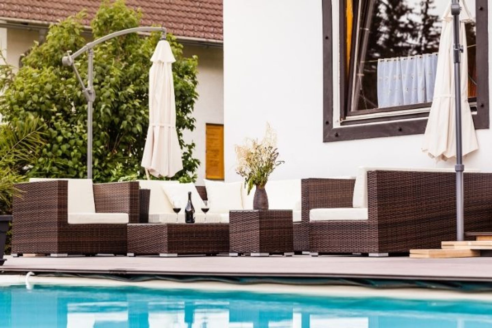 Wicker patio furniture arranged for comfortable poolside lounging