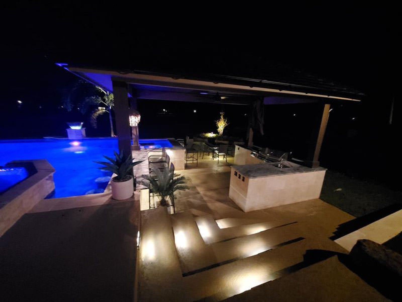 Illuminated Houston outdoor kitchen featuring a modern poolside design and ambient lighting