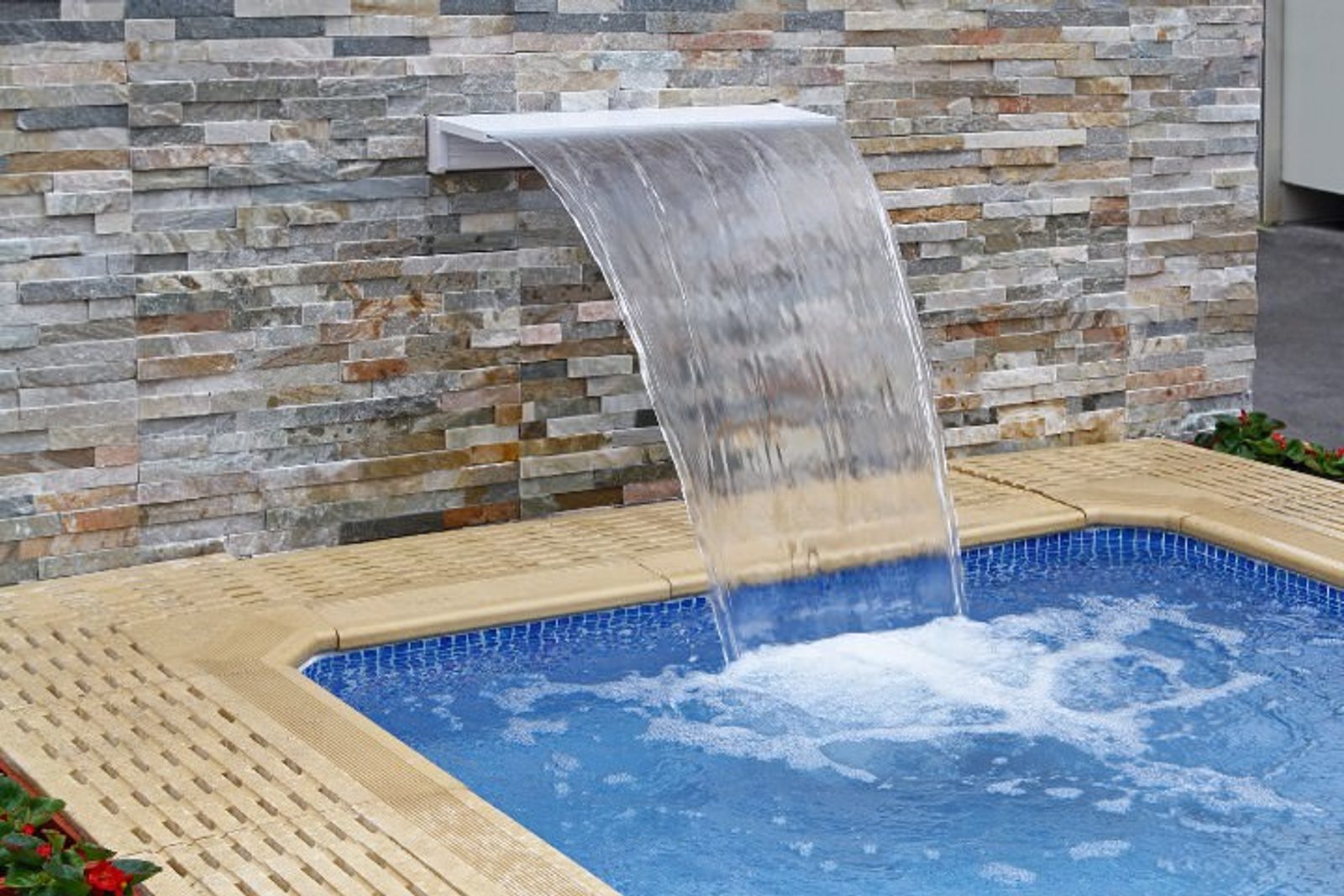 Functional and aesthetic pool spa water feature attached to a stonewall