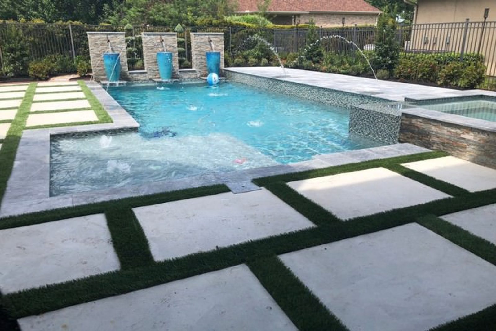 Custom stone paver landscaping around pool and luxury pool elements
