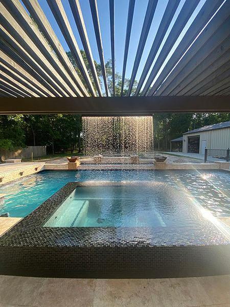 Custom swimming pool with an elevated spa and cascading water curtain feature