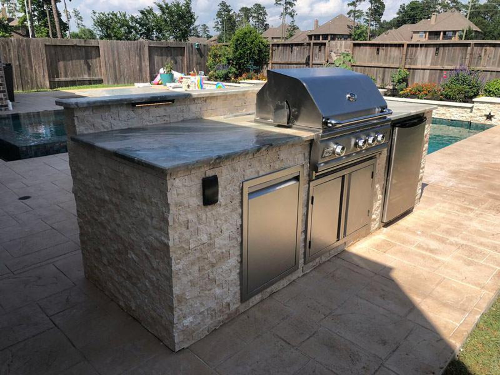 Poolside outdoor kitchen in Houston with built-in stainless grill and modern stone finish