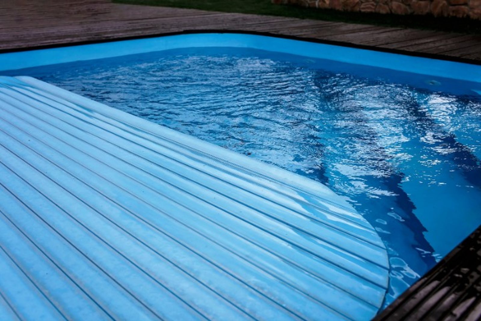 Automatic pool cover partially rolled out over a backyard pool, pool upgrade