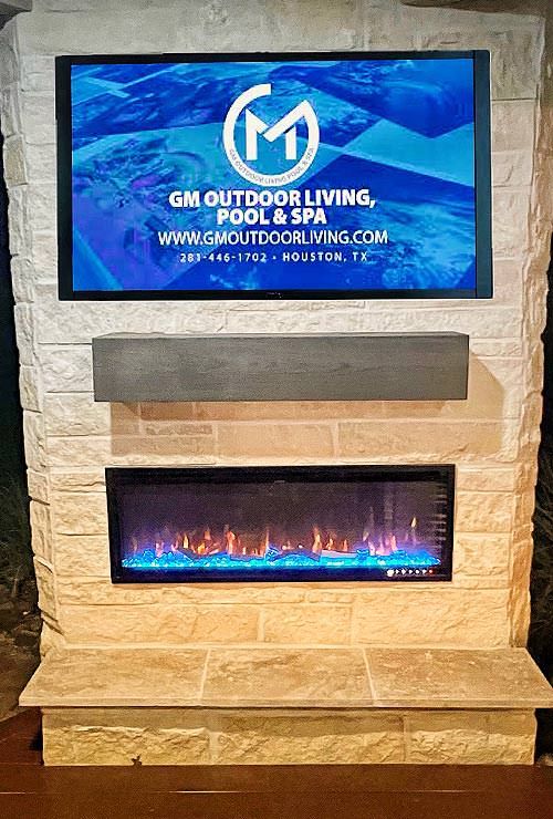 Modern outdoor living space featuring a stone fireplace with a mounted TV