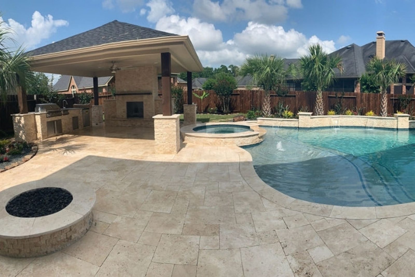Custom Houston outdoor living space with poolside fire pit and stone fireplace