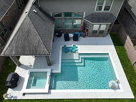 Rectangular backyard swimming pool with integrated spa and spacious pool deck