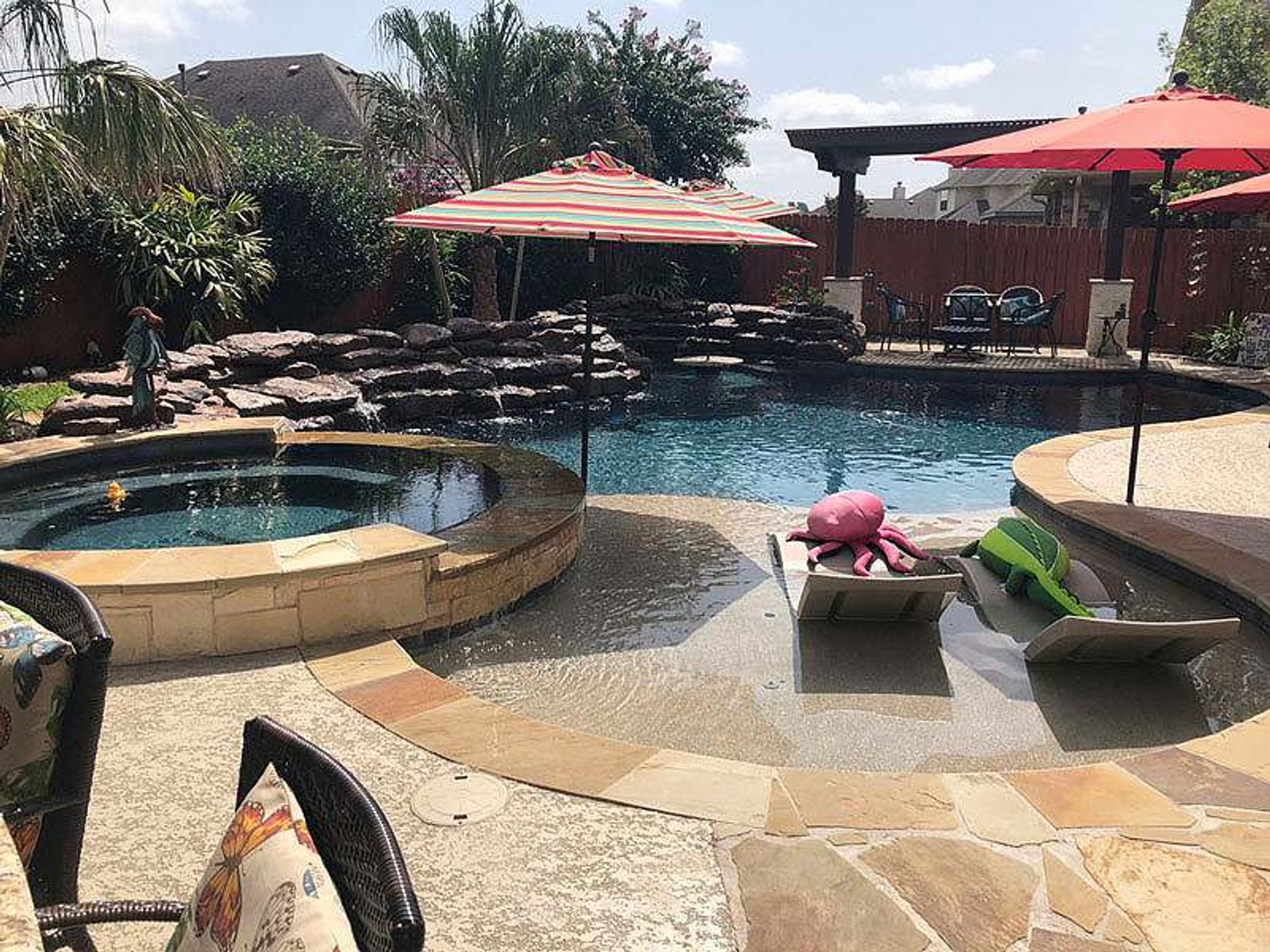 Family-friendly pool design with a shallow tanning ledge, integrated spa, and rock waterfall feature