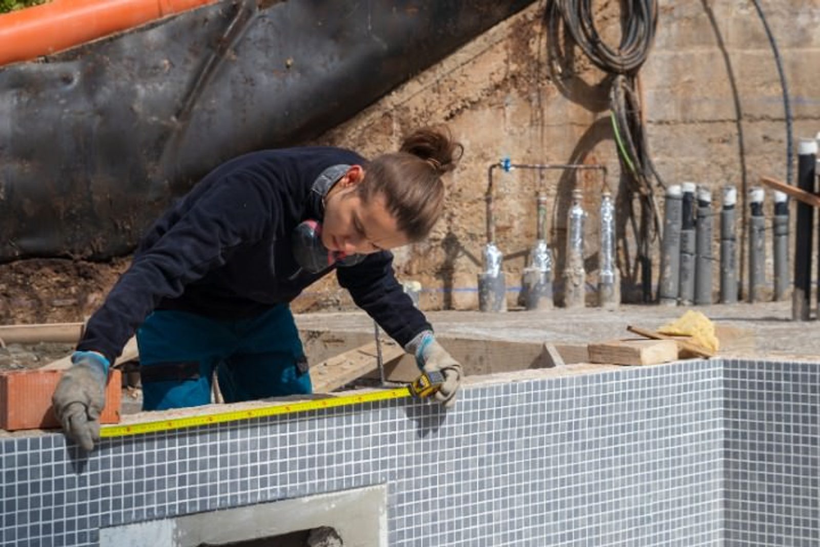 Pool construction worker measuring the edge of a pool under construction